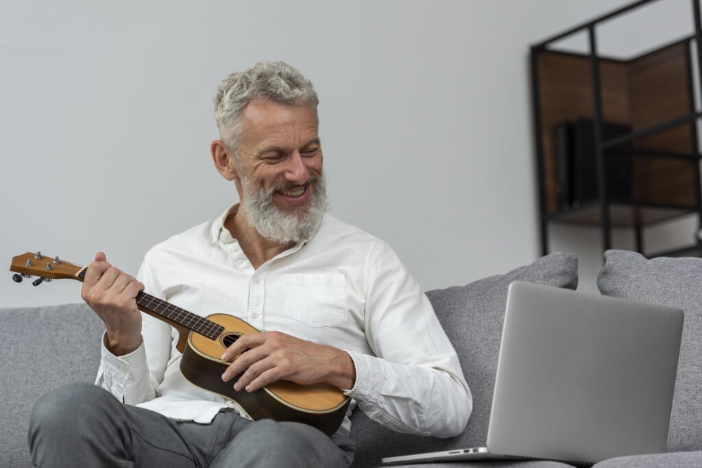 dedilhado de imagine no ukulele. Imagem de homem grisalho com barba e camisa branca tocando ukulele